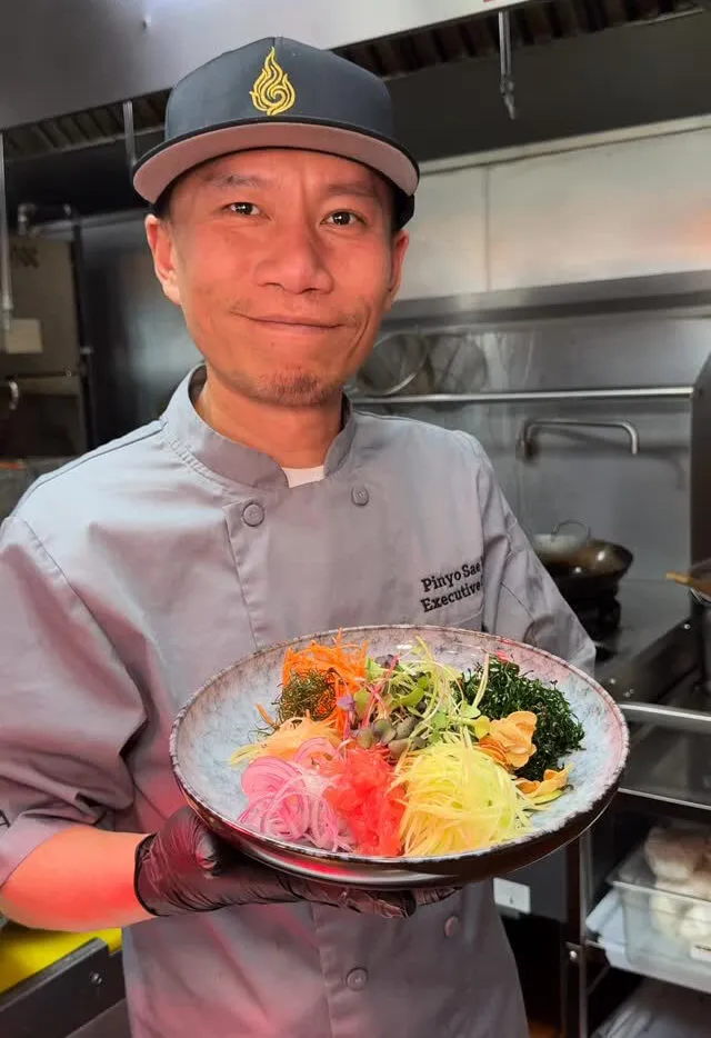 Chef Pinyo holding a plated dish in the Amata kitchen